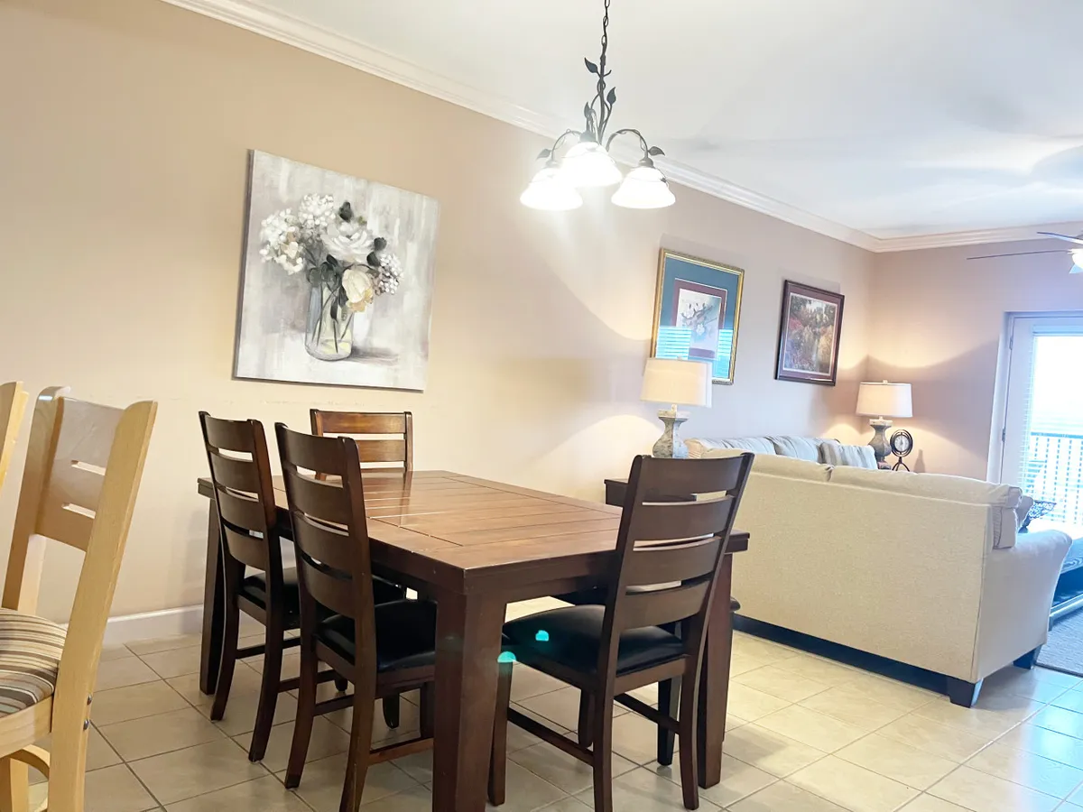 A warm, welcoming interior scene displays a dining table, floral painting, sofa, and table lamp. The setting suggests a comfortable spot for gathering with friends and family after a day out, emphasizing relaxation and socializing in between local adventures.