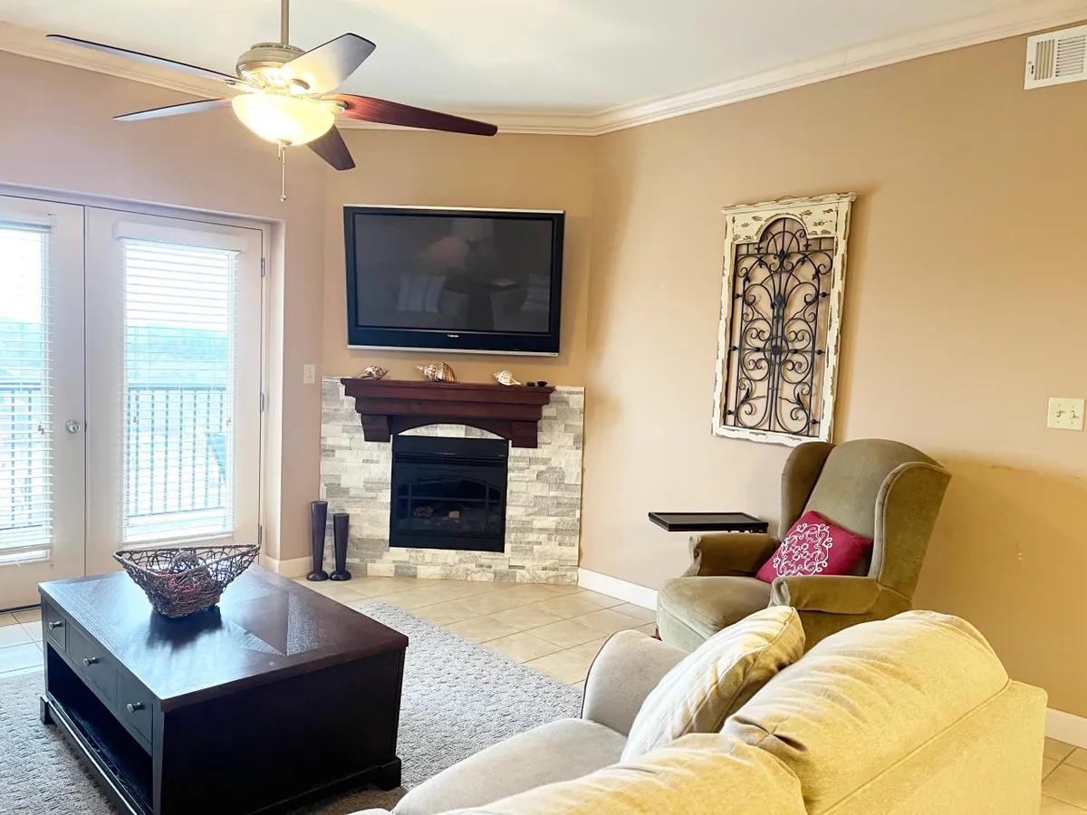 A cozy living area with a sofa, coffee table, television, and a fireplace. Large windows likely connect to a balcony, hinting at the views available from the room. The arrangement showcases a comfortable space to relax right after check-in.
